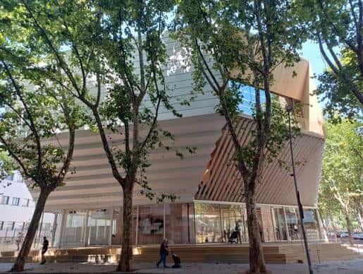 Vista exterior de la biblioteca desde la calle con árboles