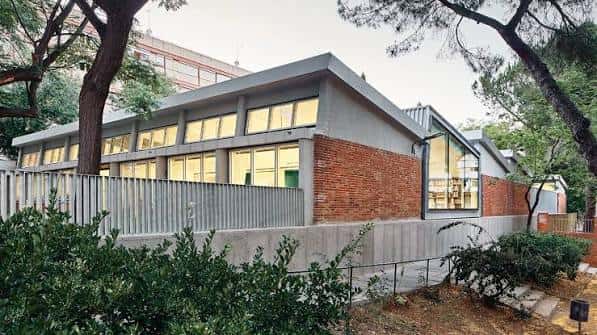Vista lateral del edificio mostrando muros de ladrillo y estructura moderna rodeada de vegetación