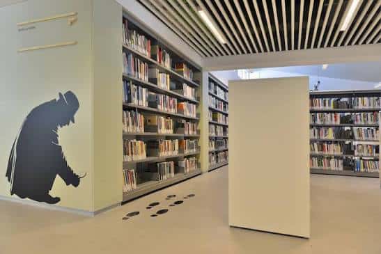 Interior de la sala de lectura con estanterías, suelo limpio y silueta decorativa en la pared