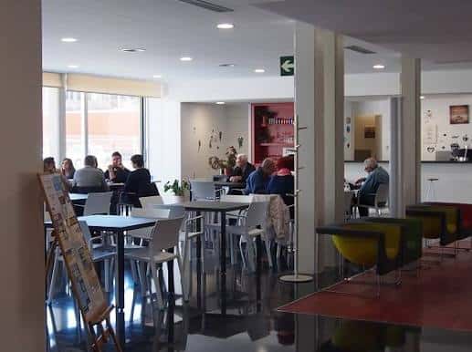 Interior del centro comunitario con personas reunidas en mesas