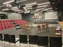Sala de eventos interior con butacas rojas y escenario