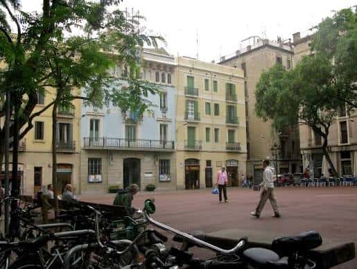 Plaza de la Vila de Gràcia con personas caminando y bicicletas en primer plano