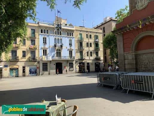 Fachada del ayuntamiento de Gràcia con banderas y barreras metálicas en la plaza