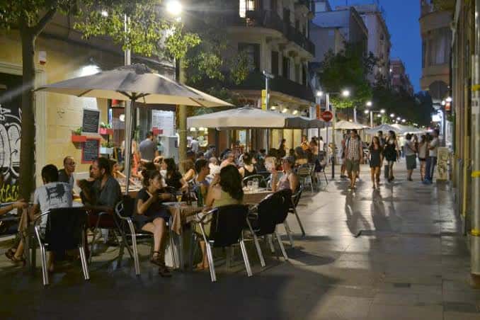 Ambiente nocturno en Carrer de Blai con gente cenando al aire libre bajo luces cálidas