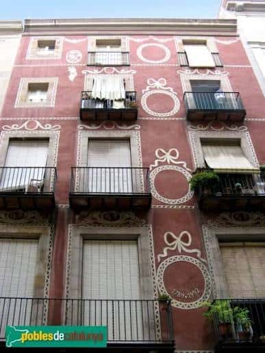 Vista frontal del edificio con decoración en tonos rojos y blancos, típica de la arquitectura catalana
