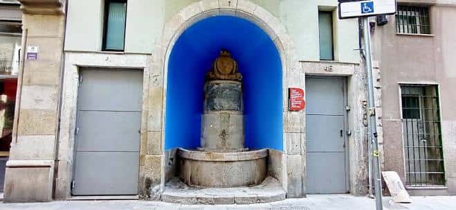Fuente histórica del Carrer Nou de la Rambla, ubicada en un arco de piedra con fondo azul