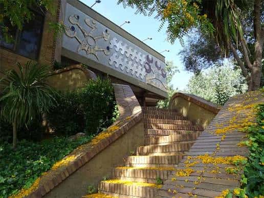 Escalinata exterior con mosaicos artísticos y vegetación alrededor del museo