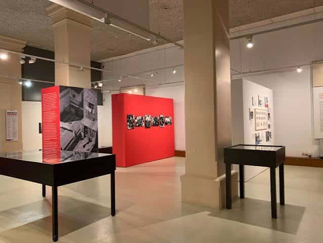 Interior de la sala de exposiciones con paneles rojos y fotografías enmarcadas