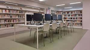 Área de trabajo con ordenadores y estanterías de libros en la biblioteca