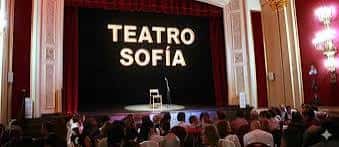 Escenario del Teatro Sofía con pantalla que muestra el nombre del teatro y público en primer plano