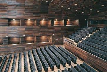 Interior del auditorio con asientos en gradas y revestimiento de madera