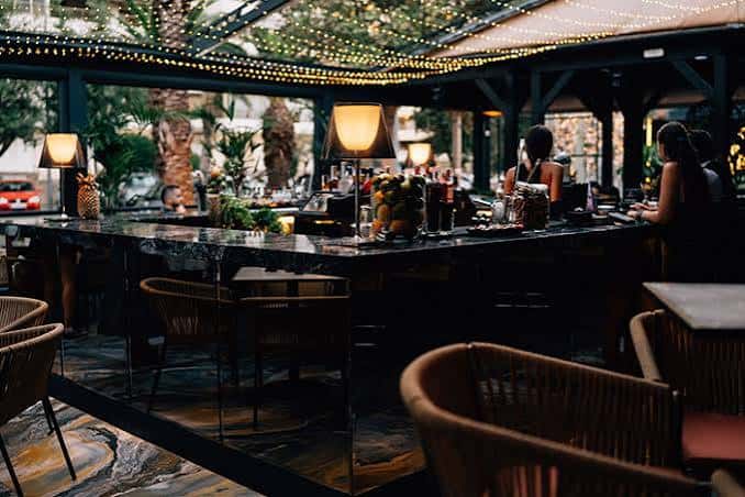 Terraza exterior del club con mesas, lámparas y ambiente relajado
