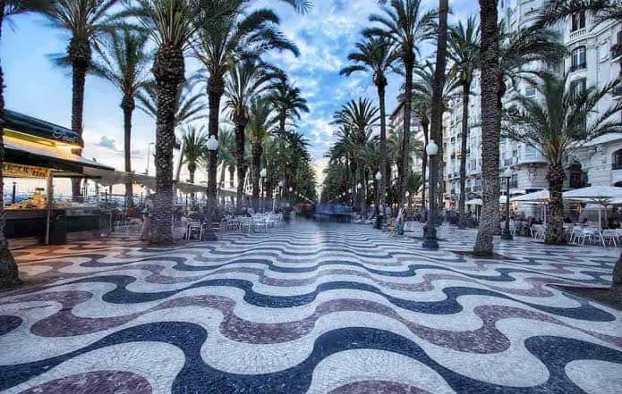 Paseo de la Explanada de España con palmeras y terrazas de cafeterías al atardecer
