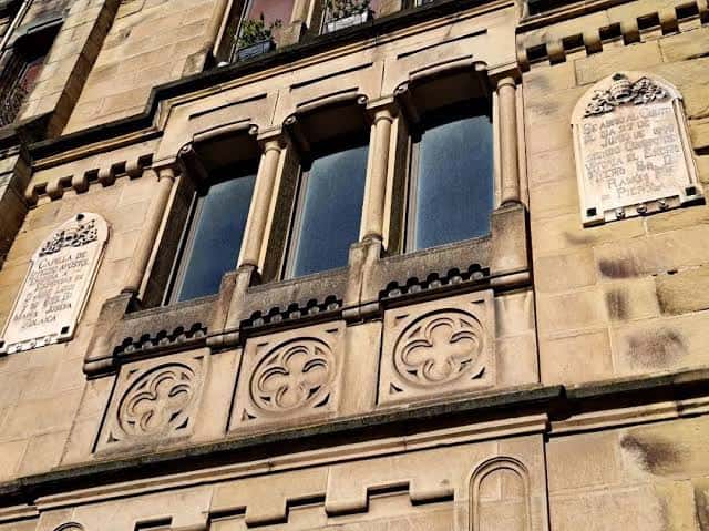 Detalle arquitectónico de la fachada de la capilla con ventanas y placas conmemorativas