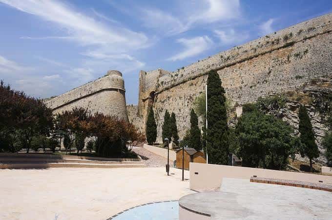 Plaza exterior frente a las murallas del Castillo de Ibiza con vegetación