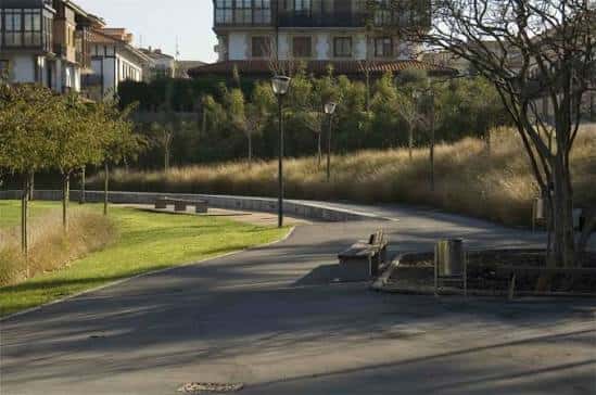 Camino curvo con bancos y vegetación en el parque Alai Txoko