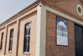 Detalle arquitectónico de la fachada de ladrillo con ventanales y cartel de exposición
