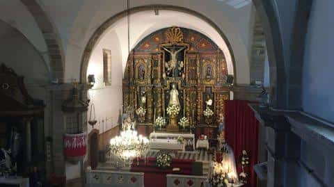 Interior de la iglesia con altar principal, retablo dorado y decoración para celebración