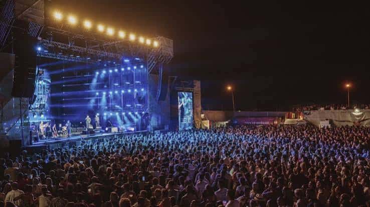 Escenario del festival Doñana Music Experience con luces amarillas y gran afluencia de público