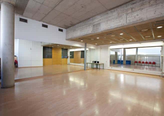Sala de ensayo o eventos con suelo de madera y espejos en el Centre Cívic Ateneu Fort Pienc