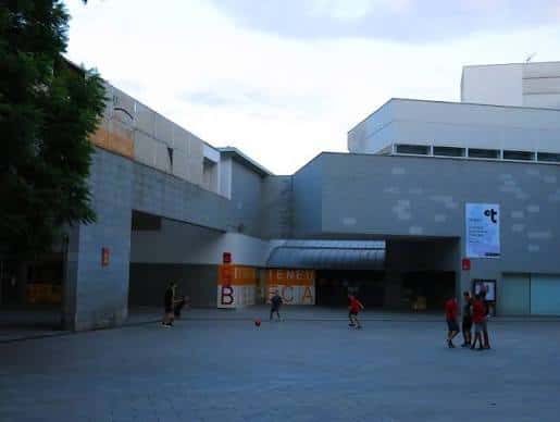 Vista exterior del Centre Cívic Ateneu Fort Pienc con personas jugando al fútbol en la plaza