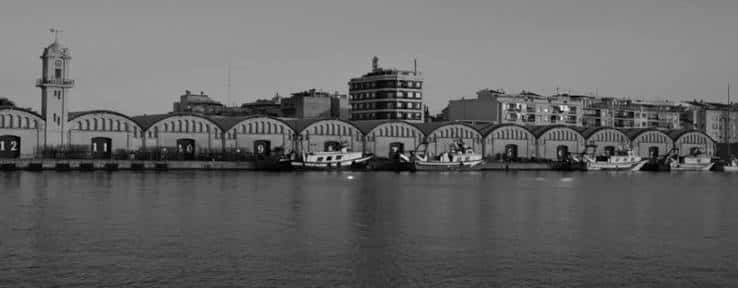 Fachada de los tinglados históricos del puerto en blanco y negro con embarcaciones atracadas
