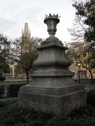 Detalle de la escultura de La Copa en un entorno urbano con árboles