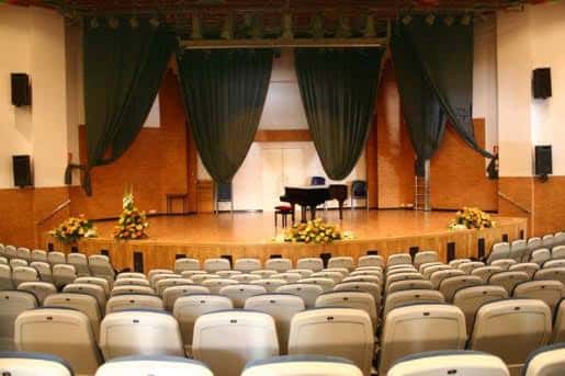 Interior del auditorio con escenario, piano y butacas dispuestas para eventos