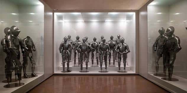 Galería de armaduras históricas en el Museo del Ejército, mostrando una colección ordenada de cascos y corazas en un espacio expositivo moderno