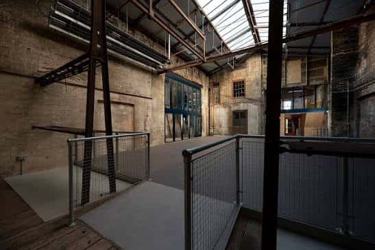 Vista del mezzanine y galería del almacén con barandillas metálicas y techo de cristal