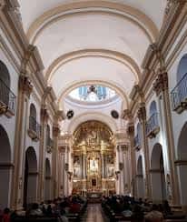 Interior de la iglesia con bóvedas, columnas y altar mayor dorado, mostrando su arquitectura religiosa
