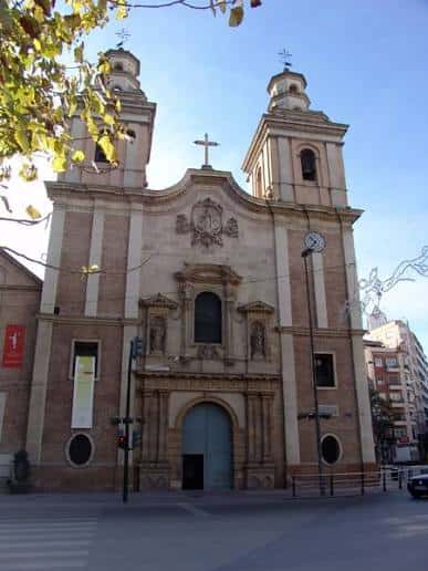 Vista frontal de la iglesia con árboles en primer plano y cielo azul, ideal para eventos al aire libre