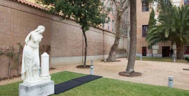 Jardín interior del centro con estatua blanca y árboles