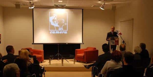 Sala de conferencias con presentación en pantalla y público