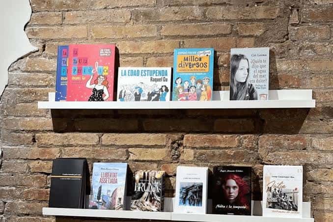 Estantería de libros sobre pared de ladrillo en el interior de La BOOKtiga