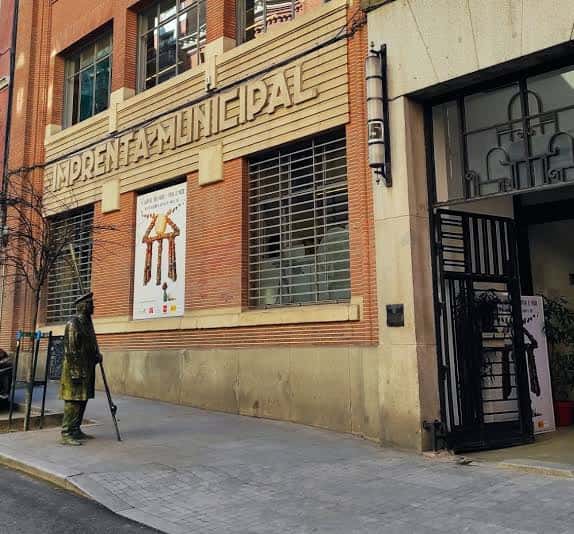 Entrada principal con cartel de exposición y estatua frente al edificio