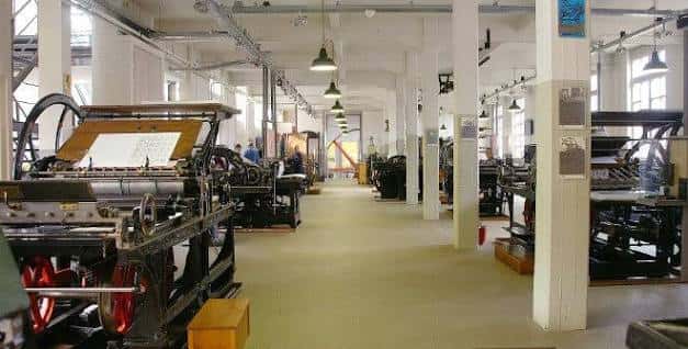 Interior del museo con máquinas de imprenta históricas en funcionamiento