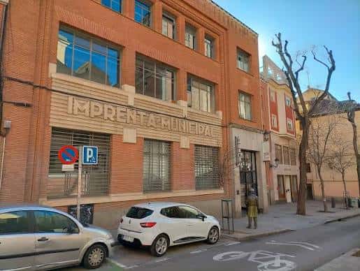 Fachada exterior con coches aparcados y señalización de tráfico