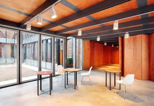 Sala de exposiciones con techos de vigas de madera y grandes ventanales