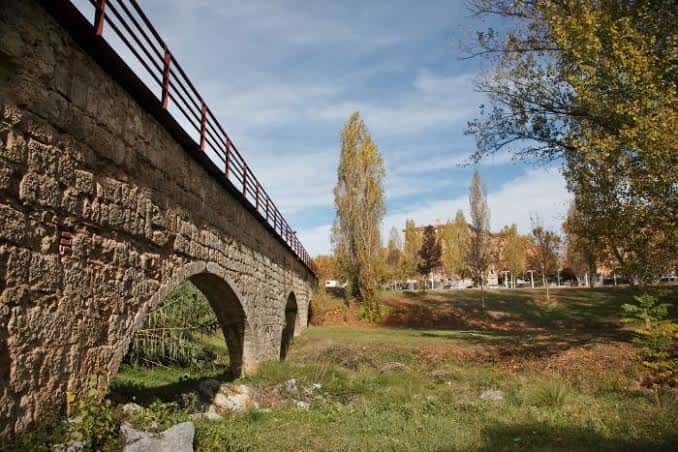 Detalle arquitectónico del puente histórico con arcos de piedra y barandilla metálica