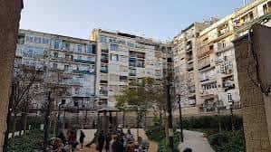 Espacio interior del jardín con edificios residenciales al fondo y personas reunidas
