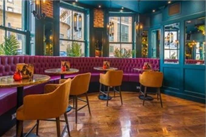 Interior del salón con sofás acolchados color magenta y mesas para eventos