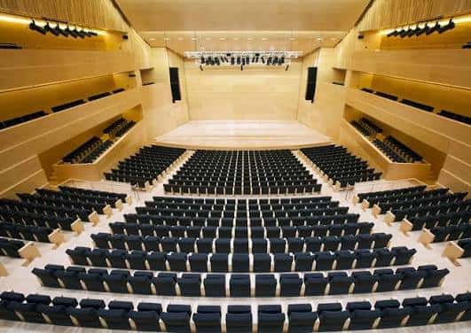 Interior del auditorio con iluminación cálida y diseño arquitectónico moderno