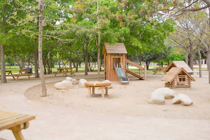 Zona de juegos infantiles con columpios y estructuras de madera