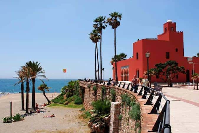 Castillo de Bil Bil desde el paseo marítimo con palmeras y playa al fondo