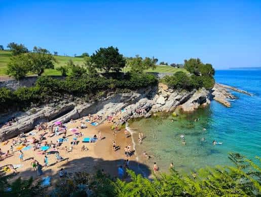 Vista panorámica de la Playa de Los Molinucos con bañistas y mar turquesa
