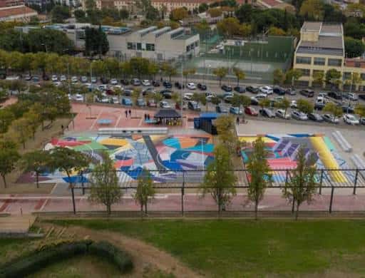 Vista aérea del parque mostrando áreas deportivas y zonas de esparcimiento con coloridos murales