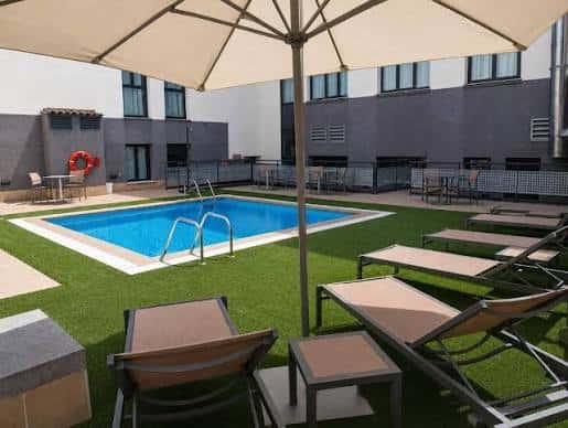Piscina exterior del hotel con tumbonas y sombrillas en un entorno relajante