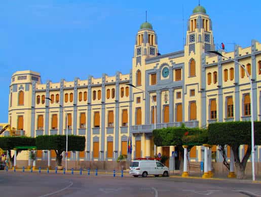 Fachada principal del Palacio de la Asamblea con tonos cálidos y vehículos en primer plano