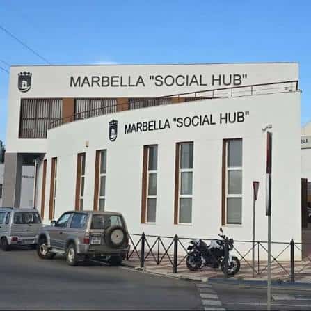 Vista frontal del edificio Marbella Social Hub con vehículos estacionados